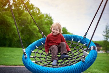 2 yıl boyunca çocuk bahçesinde salıncakta sallanırken gülen bir çocuğun açık hava portresi..