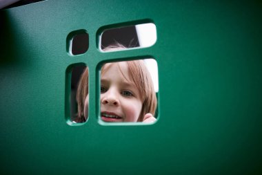 Oyun parkına tırmanan sevimli anaokulu çocuğunun açık hava portresi..