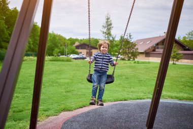 Çocuk bahçesinde salıncakta sallanan sevimli anaokulu çocuğu portresi..