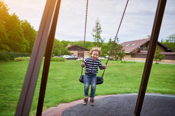 Çocuk bahçesinde salıncakta sallanan sevimli anaokulu çocuğu portresi..