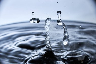 Kaynar su mavi arkaplanda buharla sıçrar..