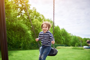 Çocuk bahçesinde salıncakta sallanan sevimli anaokulu çocuğu portresi..