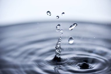 Kaynar su mavi arkaplanda buharla sıçrar..