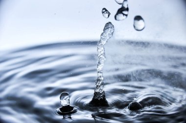 Kaynar su mavi arkaplanda buharla sıçrar..