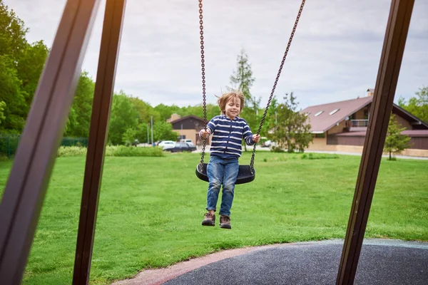 Çocuk bahçesinde salıncakta sallanan sevimli anaokulu çocuğu portresi..