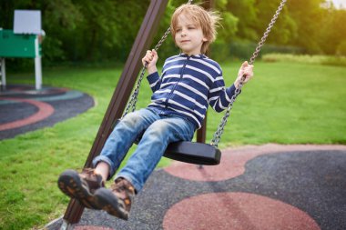 Çocuk bahçesinde salıncakta sallanan sevimli anaokulu çocuğu portresi..