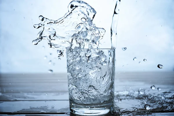 Вода Яку Потрібно Випити Вливається Склянку Синьому Фоні Студійного Дробу — стокове фото