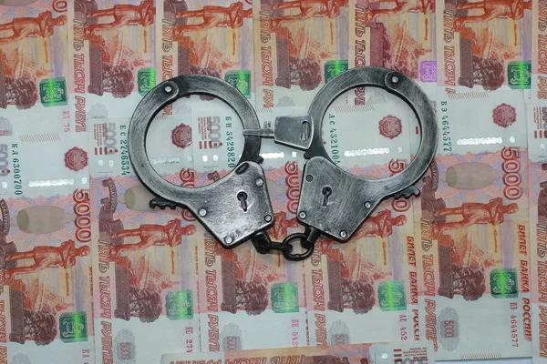 Handcuffs with a key lie on Russian bills — Stock Photo, Image