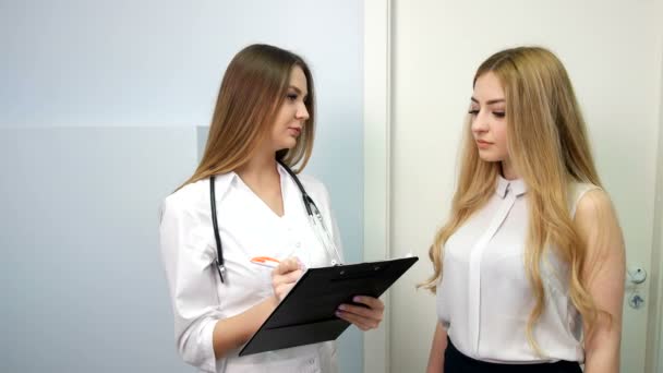 Läkaren och patienten diskutera något medan läkare pekar in i medicinsk historia. — Stockvideo