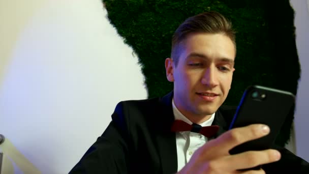 Masada oturan ve smartphone kullanarak gülümseyen adam — Stok video