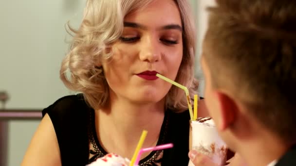 Close-up van een man en vrouw behandelen elkaar milkshakes — Stockvideo