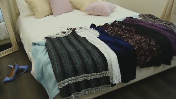 Много разных платьев на кровати — стоковое видео