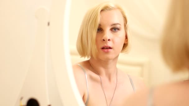 Reflectie in de spiegel van jonge vrouw die haar wimpers verven — Stockvideo
