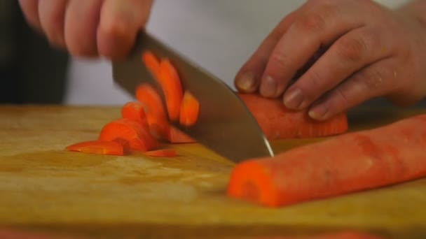 Vista lateral mulher cozinheiro corta cenoura em meio-anéis em uma placa de corte de madeira — Vídeo de Stock