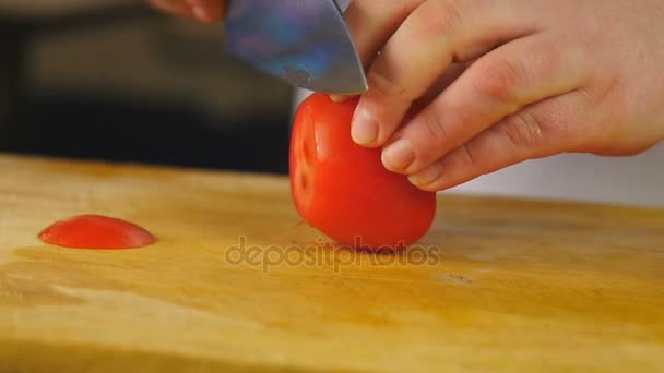 Vista lateral mulher cozinheiro corta tomate em fatias em uma placa de corte de madeira — Vídeo de Stock