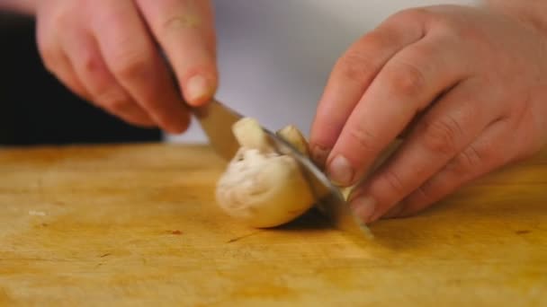 Vista laterale cuoco taglia funghi su un tagliere di legno — Video Stock