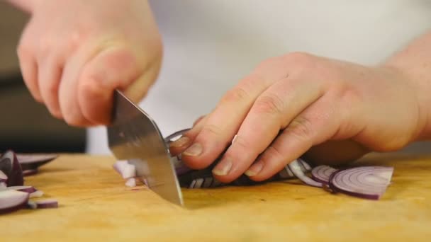 Side view cook csökkenti a lilahagyma felét karikákra, és foszlányait, hogy a fa vágódeszka — Stock videók