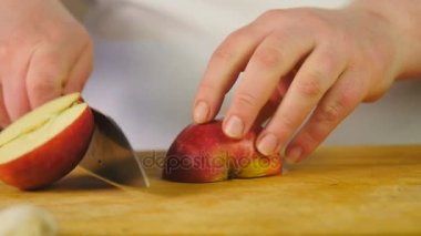 Yan görünümü Şef yarı-halkalar tahta kesme tahtası üzerinde içine Kırmızı elma cuts