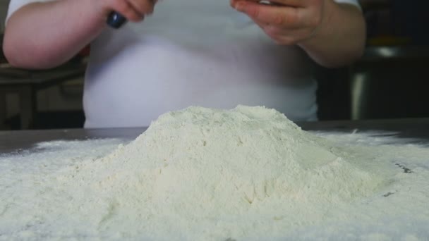 Zblízka boční pohled žena kuchař rozbije vajíčko s nožem a vhodí ji do mouky — Stock video