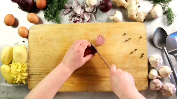 Top view cocinero corta salchichas en rodajas en una tabla de cortar — Vídeo de stock
