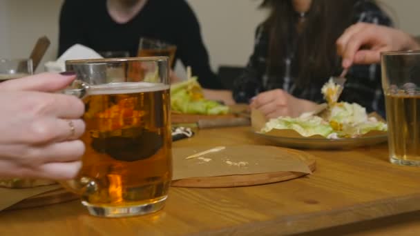 Cierre la comida y la bebida en la mesa y la mano femenina toma una taza de cerveza — Vídeo de stock
