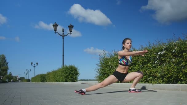 Meisje in sports shirt en broek benen voor fitnesstraining uitrekken — Stockvideo