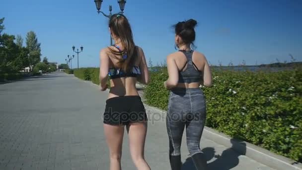 Young women in sports clothes run along the embankment — Stock Video