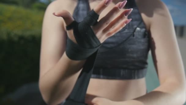 Close up jovem mulher coloca bandagens elásticas em sua mão na rua — Vídeo de Stock