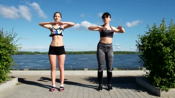Спортивные девушки в спортивной одежде делают тело растягиваясь на набережной — стоковое видео