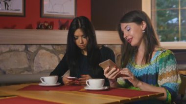 Fotoğraf ve video bir kafede onların smartphones içinde kadınlar izle