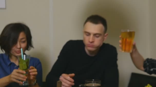 Gros plan verres clink jeunesse avec des boissons alcoolisées assis à une table dans un bar — Video