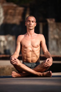Genç adam yoga yapar.