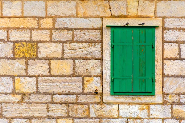 La fachada de una antigua casa de piedra con una ventana con persianas verdes — Foto de Stock