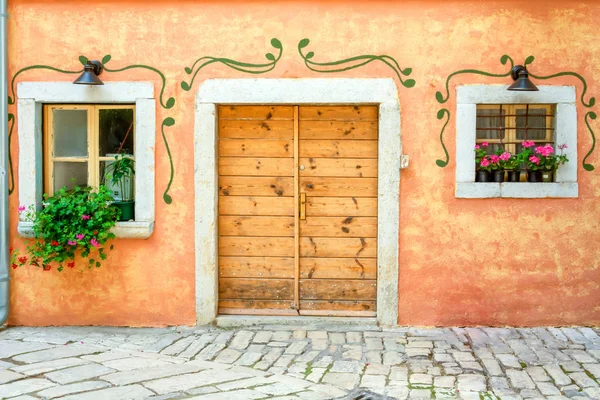 Fachada de una antigua casa con puerta y ventana y flores en maceta — Foto de Stock