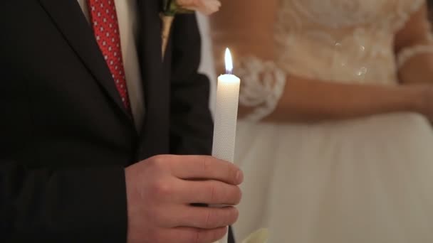 Мужчина держит свечу в церкви на свадебной церемонии — стоковое видео