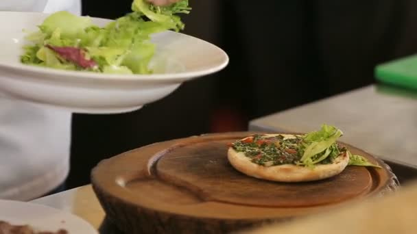 Chef-kok legt groene sla blad op een hamburger brood — Stockvideo