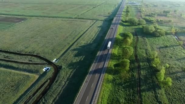 4 k εναέρια πλάνα ενός φορτηγού ιππασίας σε ένα δρόμο μεταξύ πράσινο πεδία τον ήλιο να ανατέλλει — Αρχείο Βίντεο