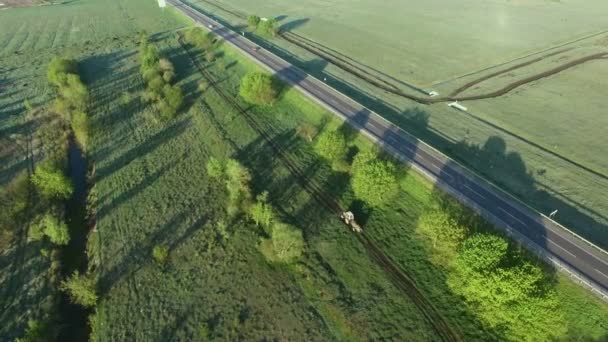4K аерофотозйомка трактора, що їде по польовій дорозі вздовж дороги — стокове відео