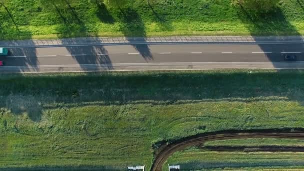 4k Luftaufnahmen von Autos Fahrzeuge Busse fahren auf einer Straße zwischen grünen Feldern in der Sonne aufgehen — Stockvideo