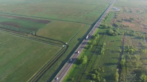 Imágenes aéreas de 4K de coches montados en una carretera entre campos verdes al amanecer — Vídeos de Stock