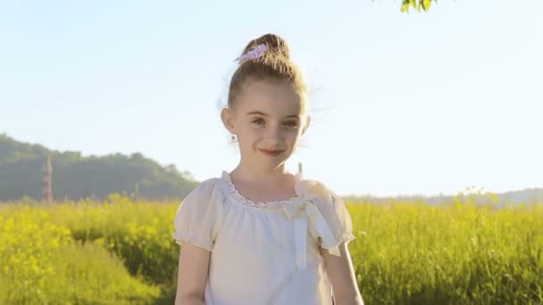 Uma menina adorável coloca um par de óculos de sol e sorrisos — Vídeo de Stock