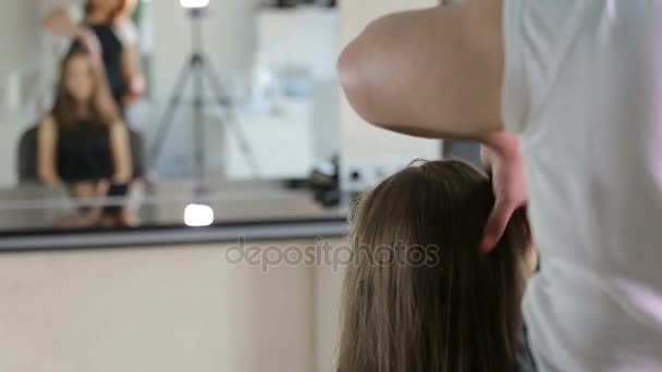 Парикмахер, парикмахер готовит девушку-подростка в белом гримерной для парикмахерской — стоковое видео