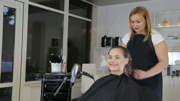 美发师梳理头发的十几岁的女孩在美发沙龙中的客户端 — 图库视频影像