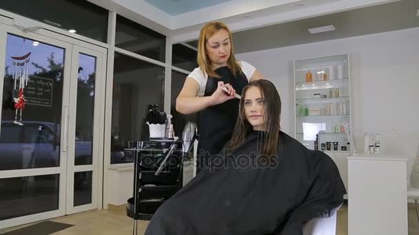 Hairdresser combing hair of teen girl client in hair salon — Stock Video