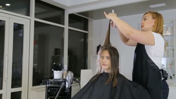 Frisören kamning och cuting hår tonåring flicka client i frisersalong — Stockvideo
