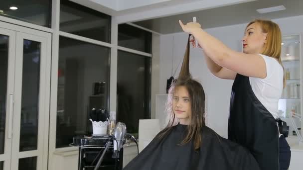 Friseur kämmt und schneidet im Friseursalon Haare von Teenie-Mädchen — Stockvideo