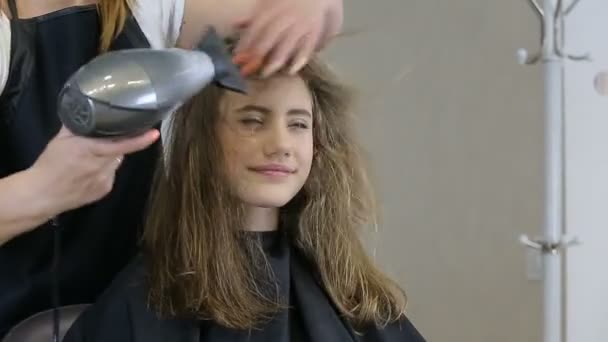 Profesional peluquero seca el cabello de adolescente linda chica — Vídeo de stock