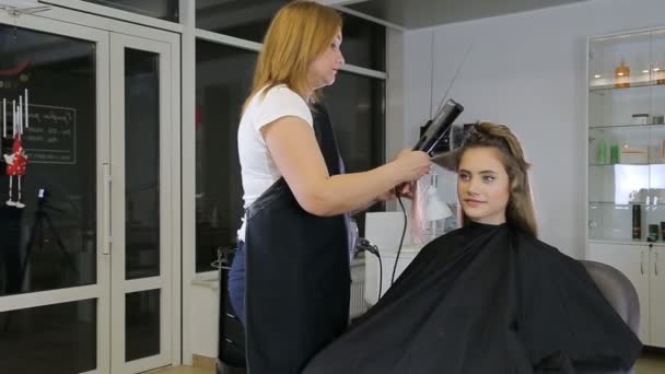 Professional hairdresser stylist curling up teen girl hair — Stock Video