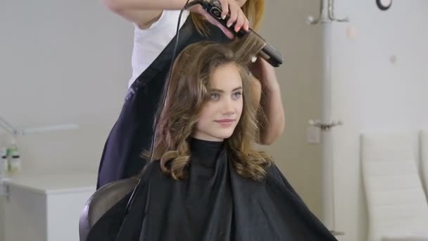Профессиональный парикмахер скручивает волосы девушки-подростка — стоковое видео