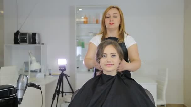 Professional hairdresser, stylist finishes hairstyle for teen girl — Stock Video